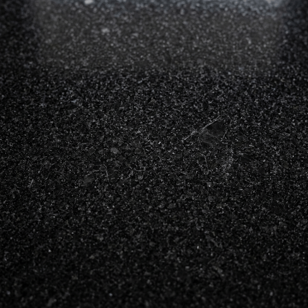 Polished black granite surface with visible speckled texture and reflections